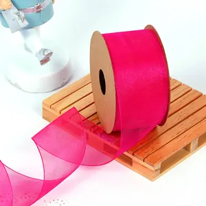 Close-up of fuchsia magenta sheer organza ribbon texture on a brown spool holder