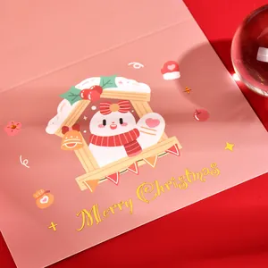 Close-up of pink Christmas card with gold foil Merry Christmas text and cute illustration