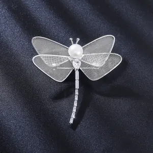 Detailed macro view of a silver dragonfly brooch with pearl and intricate mesh wings