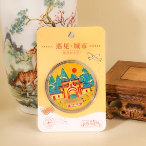 Detailed close-up of a Guilin landmark metal coin souvenir in its yellow packaging.
