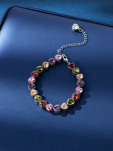 Detailed view of elegant heart-shaped colorful zirconia bracelet on blue leather background