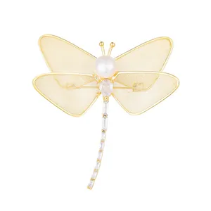 Elegant dragonfly brooch with freshwater pearl and sparkling zircon on gold mesh wings.
