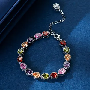 Close-up of elegant bracelet with teardrop colorful zircons on a navy blue background.