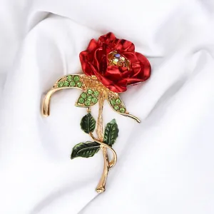Close-up detail of a vintage red rose brooch with green enamel leaves and rhinestones