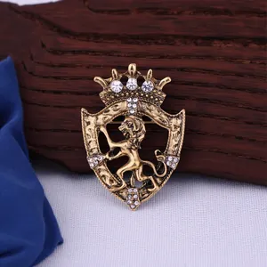 Close-up of a vintage crown lion shield brooch in antique gold finish with clear rhinestones