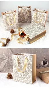 Elegante weiße und goldene Papiertüten mit Blattglitzer und festlicher Dekoration