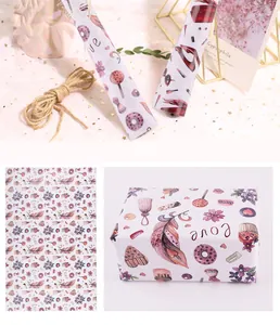 Gros plan sur du papier cadeau floral décoratif avec des plumes, donuts et motifs Love.