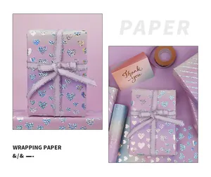 Nahaufnahme von lila Laser-Geschenkpapier mit Herzmuster, Schleife und Grußkarte.