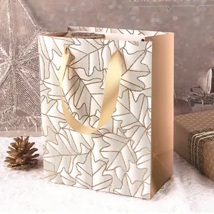 Elegante Geschenktüte aus Papier mit glitzerndem Ahornblattmuster und goldenen Seidengriffen