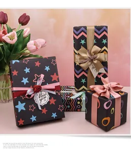 Primo piano di scatole regalo avvolte in carta da regalo nera a motivi con nastri decorativi.