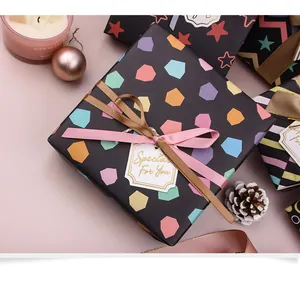 Primo piano di carta da regalo nera con motivi esagonali colorati e nastri decor