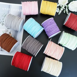Assorted colorful suede cord spools displayed on a dark surface with floral props.