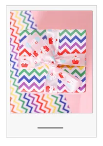 Top view detail of gift box wrapped in rainbow chevron paper with pink cupcake ribbon