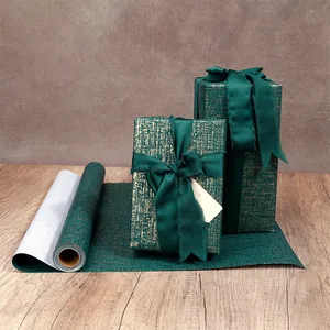 Détail d'un papier cadeau de luxe texturé vert et or sur des boîtes
