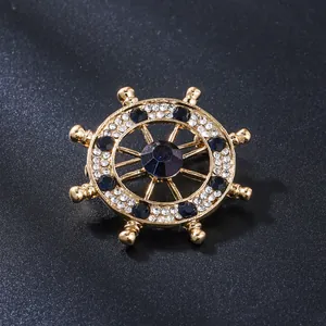 Detail of a gold-tone ship's wheel brooch decorated with blue and clear rhinestones
