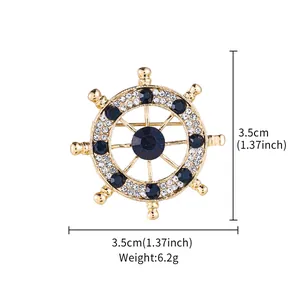 Detail showing the 3.5cm nautical wheel brooch with rhinestones and its 6.2g weight.