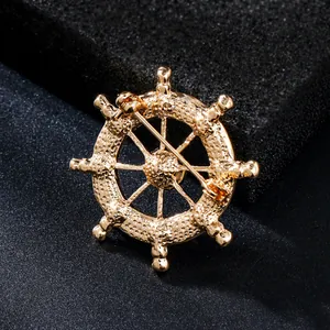 Detail view of the back of a golden ship's wheel brooch showing the safety pin fastener.