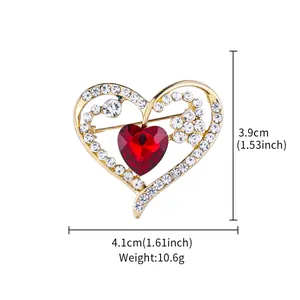 Close-up detail of heart-shaped gold brooch with red center stone and white rhinestones