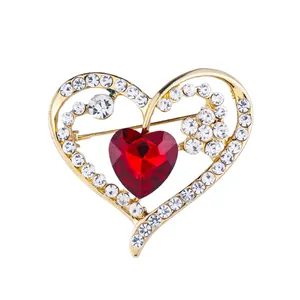 Elegant gold heart brooch pin featuring a large red gemstone and sparkling clear rhinestones