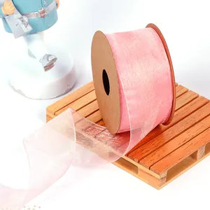Close-up of pink shimmering organza ribbon roll on a wooden mini pallet for gift wrapping