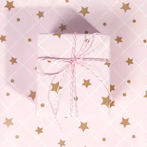 Primo piano di carta da regalo rosa con stelle dorate e motivo a griglia bianca.