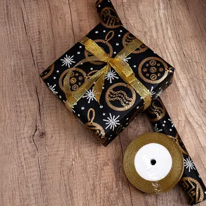 Schwarzes Weihnachtsgeschenkpapier mit goldenem Band auf Holzoberfläche für Feiertage.