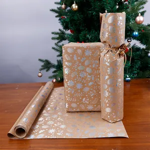 Dettaglio di motivi a pigna e fiocco di neve in lamina d'argento su carta kraft regalo