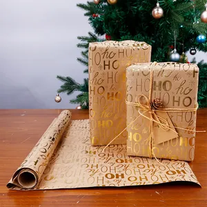 Dettaglio ravvicinato del motivo dorato 'HO HO HO' su carta da regalo kraft natalizia vintage.