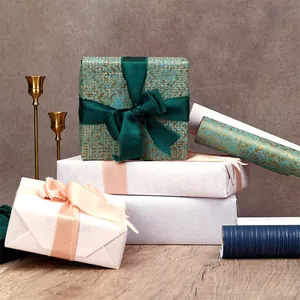 Close-up detail of luxury textured gift wrapping paper rolls in green and white.