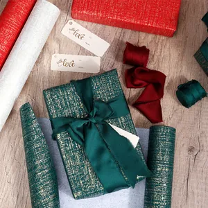 Vue détaillée d'un papier cadeau vert de luxe avec texture dorée et ruban de satin fin