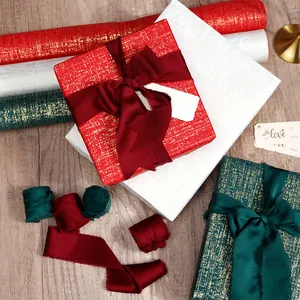Vue détaillée d'un papier cadeau de luxe texturé avec rubans de soie effilochés