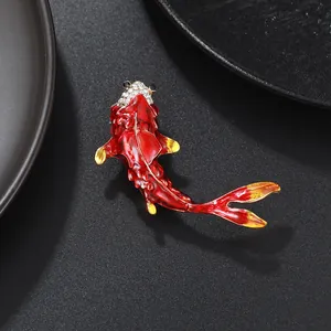 Detailed close-up of an elegant red and gold enamel koi fish brooch with crystals