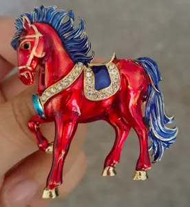 Macro view of vintage red and blue enamel horse brooch featuring sparkling rhinestones