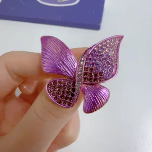 Detailed view of a purple enamel butterfly brooch featuring sparkling rhinestones.