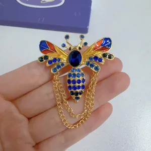 Close-up of a vintage bee brooch with colorful enamel wings and blue rhinestones.