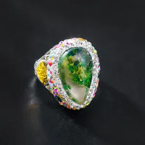 Detailansicht eines Vintage-Luxusrings mit grünem Moosstein und bunten Strasssteinen.