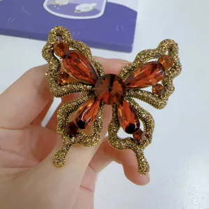 Detailed view of a vintage amber crystal butterfly brooch on a gold-tone alloy base.