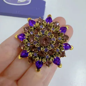 Close-up detail of a vintage floral brooch featuring purple crystals and gold alloy