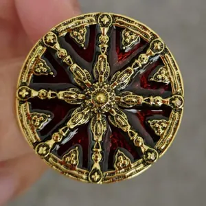 Detailed view of a vintage alloy brooch with red enamel and intricate sunburst design