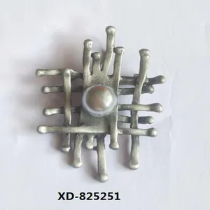 Detailed view of a vintage silver alloy brooch with an abstract grid and a central grey pearl