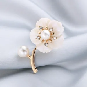 Detail view of elegant flower brooch with pearl center and rhinestone petals on silk.