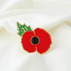 Close-up of a vintage red poppy enamel brooch on white fabric background.
