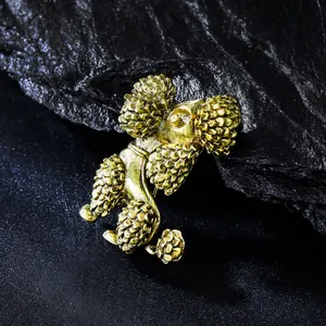 Gros plan d'une broche caniche dorée vintage avec une texture métallique sur pierre.