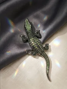 Close-up of a sparkling green rhinestone crocodile brooch with rainbow light effects
