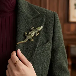Elegant gold-tone alligator brooch with green crystals on a wool blazer lapel