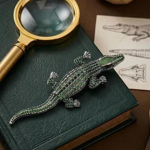 Exquisite green crystal crocodile brooch displayed on a vintage book with magnifying glass