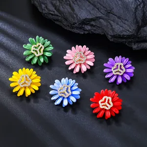 Primer plano de seis broches de margaritas de colores con centros de pedrería fina