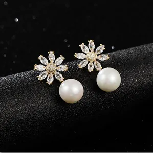 Detailopname van elegante zirkonia bloem oorbellen met grote witte parelhangers