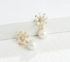 Close-up van elegante gouden bloemoorbellen met zirkonia bloembladen en ronde parels