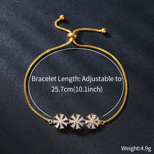 Detail of gold-plated copper bracelet with three cubic zirconia flower charms.